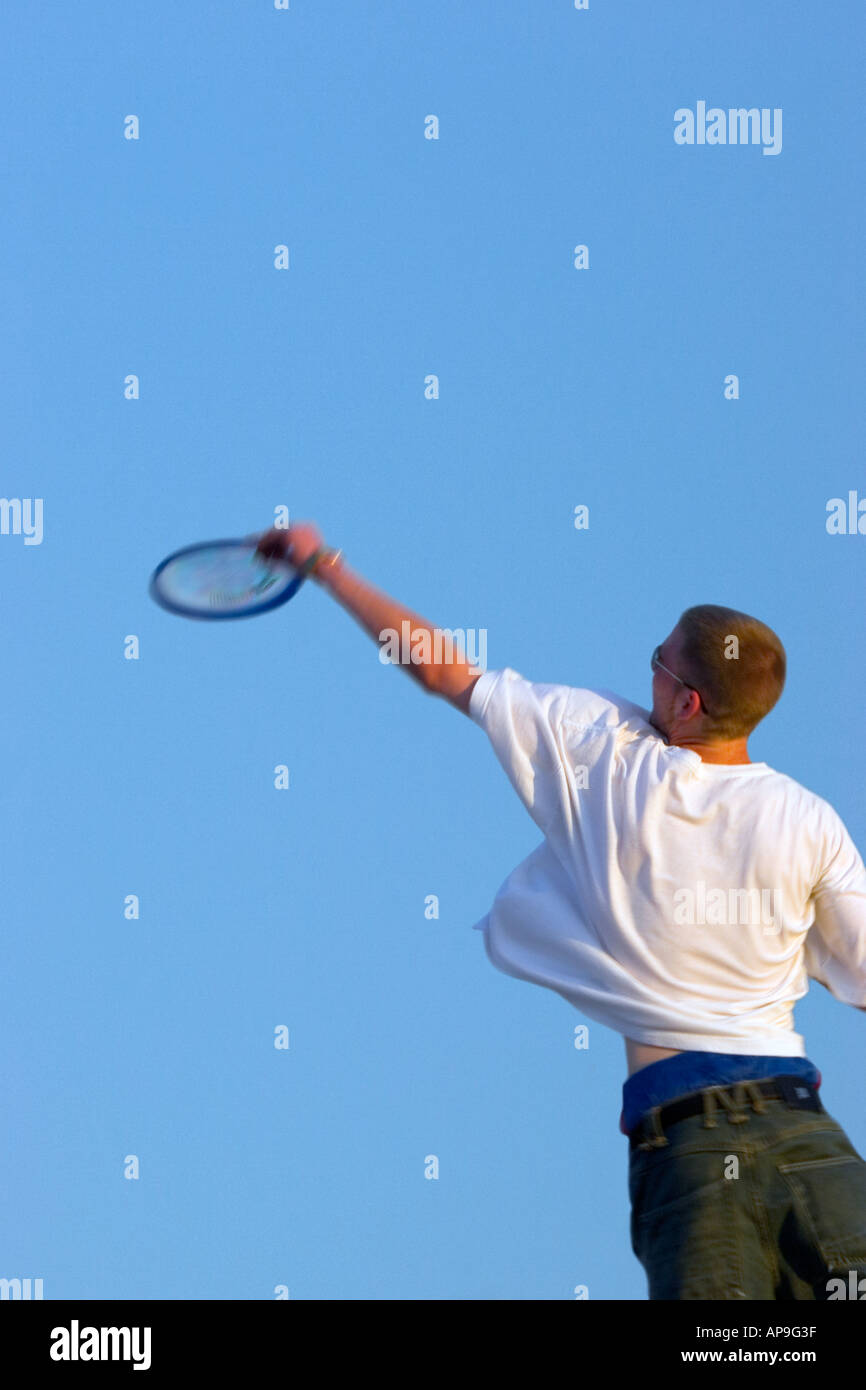 Ein junger Mann der kaukasischen springt, Arm ausgestreckt, und fängt einen Frisbee. Stockfoto