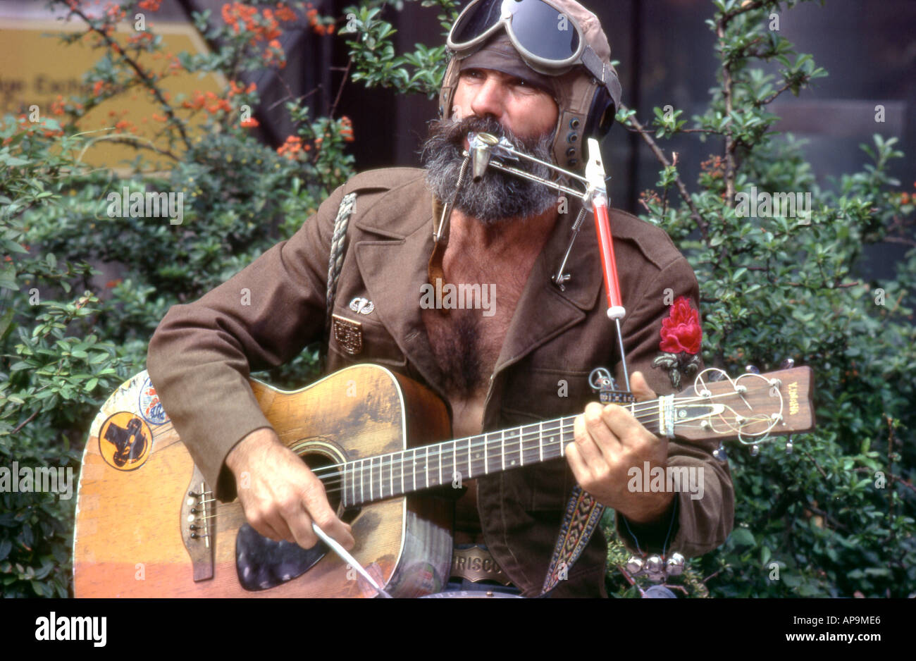 Ein haariger bärtiger 70er Jahre amerikanischer Busker Mann Musiker Gitarre spielen in Fliegerbrille auf der Straße Köln Deutschland 1977 KATHY DEWITT Stockfoto