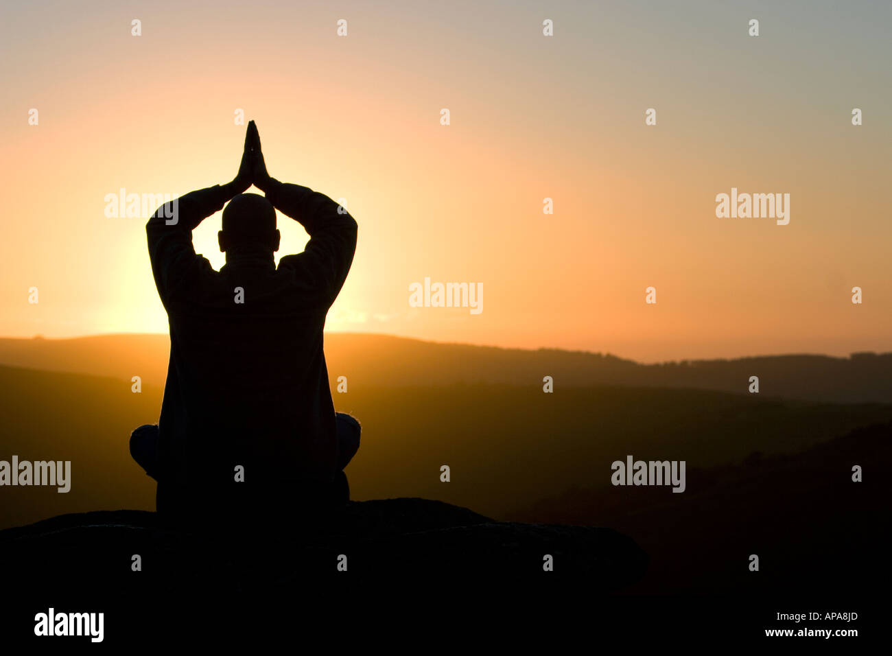 Silhouette Profil eines betenden Mannes saß auf einem Hügel bei Sonnenaufgang Stockfoto