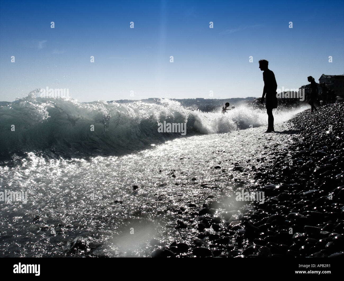 Mann steht am Rande einer Kies direkt am Meer Stockfoto