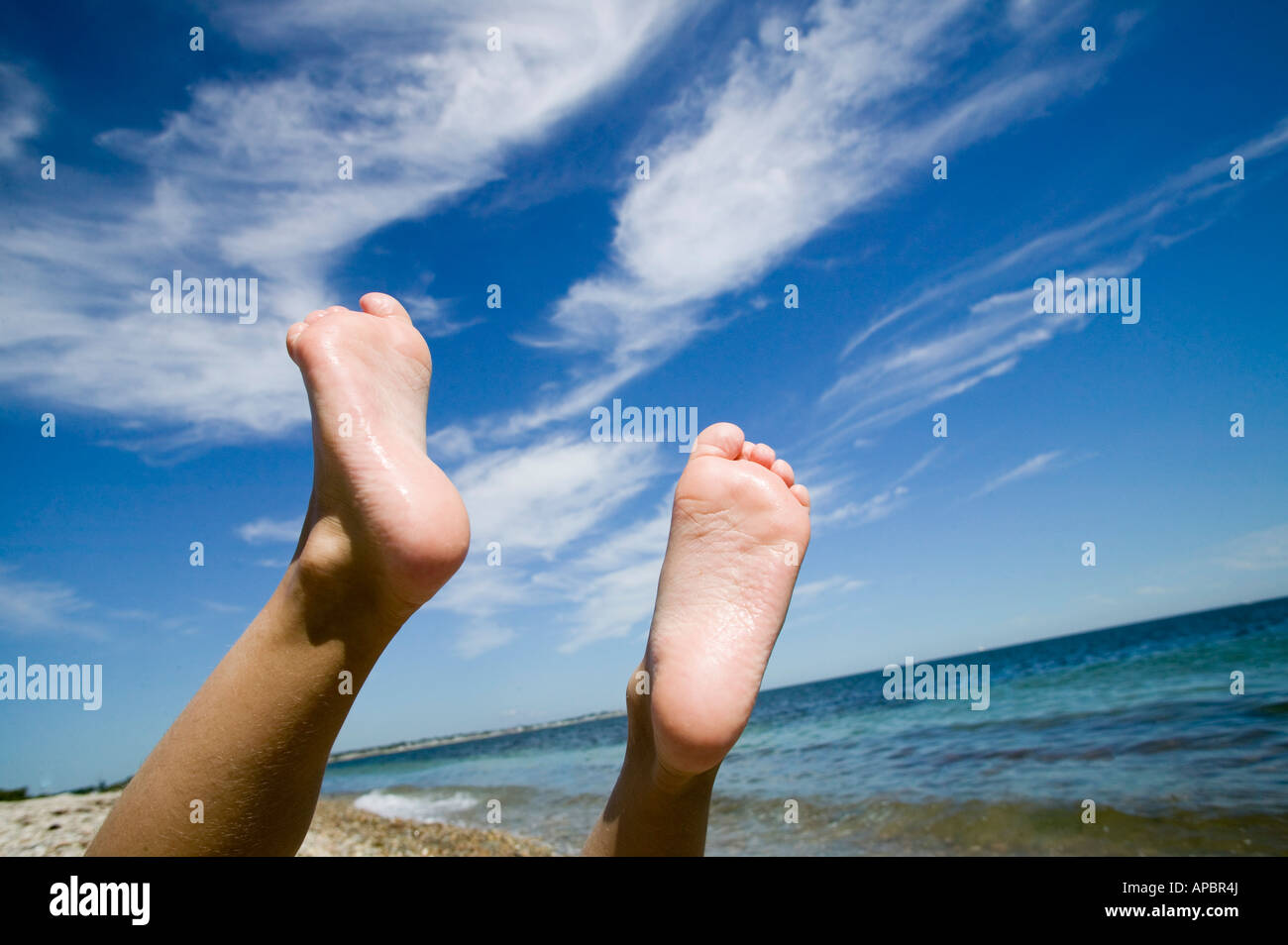 Kind spielt am Strand, die Füße in die Luft zu heben Stockfoto