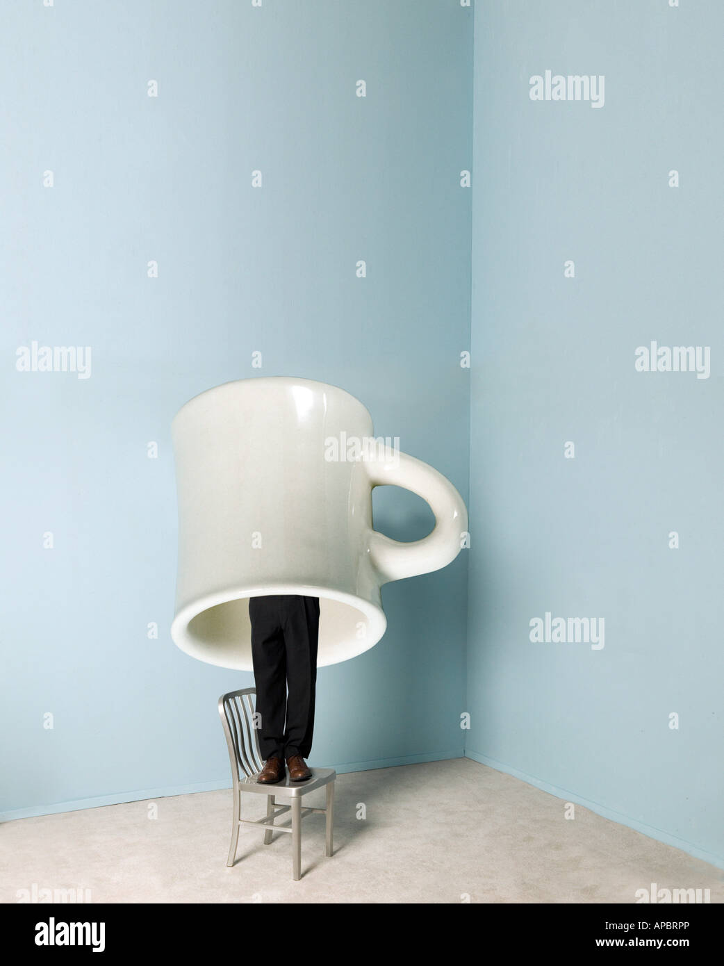 Business-Mann steht oder versteckt unter riesigen Kaffee Tasse Humor lustig Stockfoto