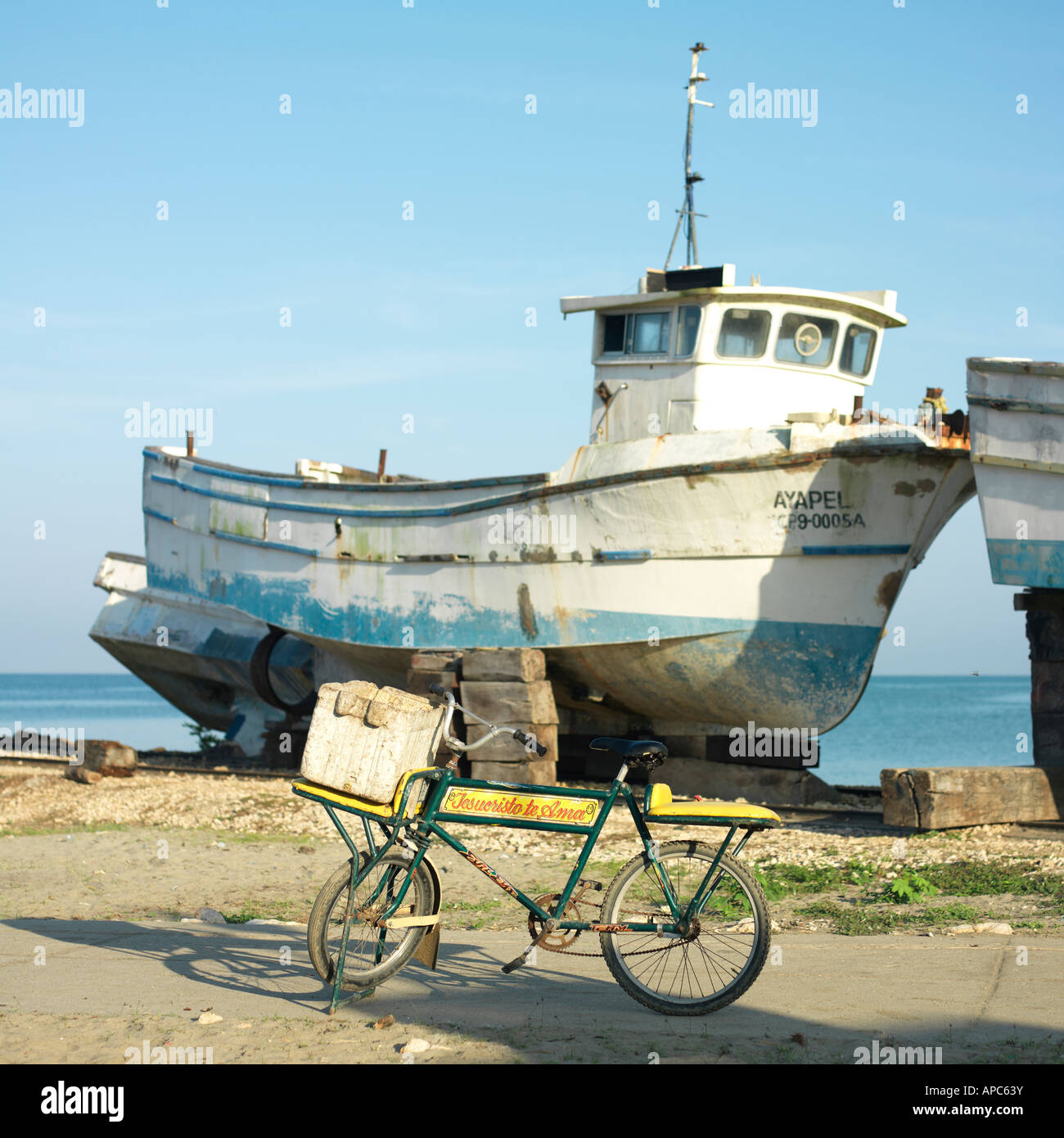 Ein Fischer Fahrrad infront von einem angedockten Fischerboot wartet auf Reparaturen. Stockfoto