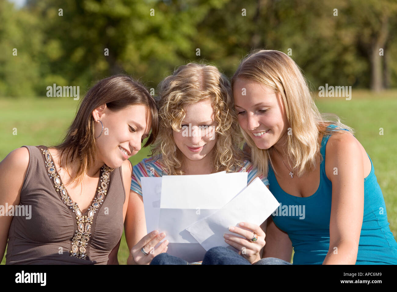 Drei junge Frauen, die zusammen einen Brief lesend Stockfoto