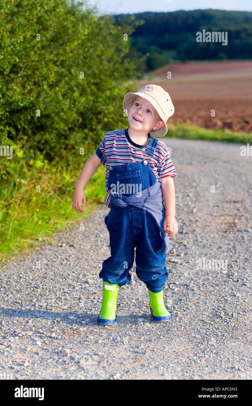Ein drei Jahre alter Junge mit Gummistiefel und einen Schlapphut Stockfoto