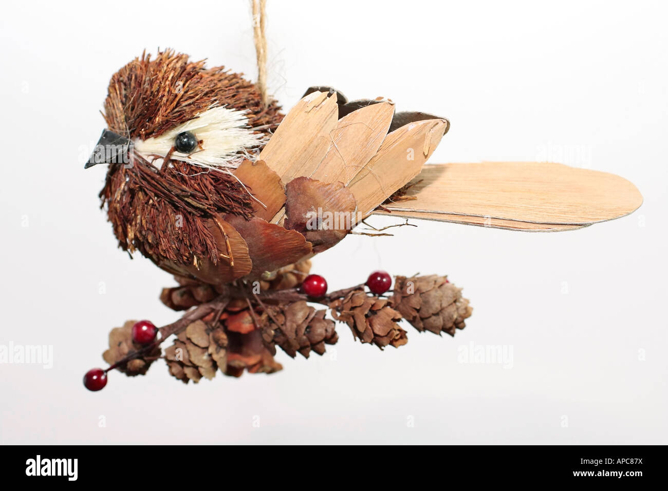 Ein süßer, kleiner Vogel, der Weihnachtsbaum hängt und aus natürlichen Materialien wie Holz, Kiefernzapfen und Beeren besteht Stockfoto