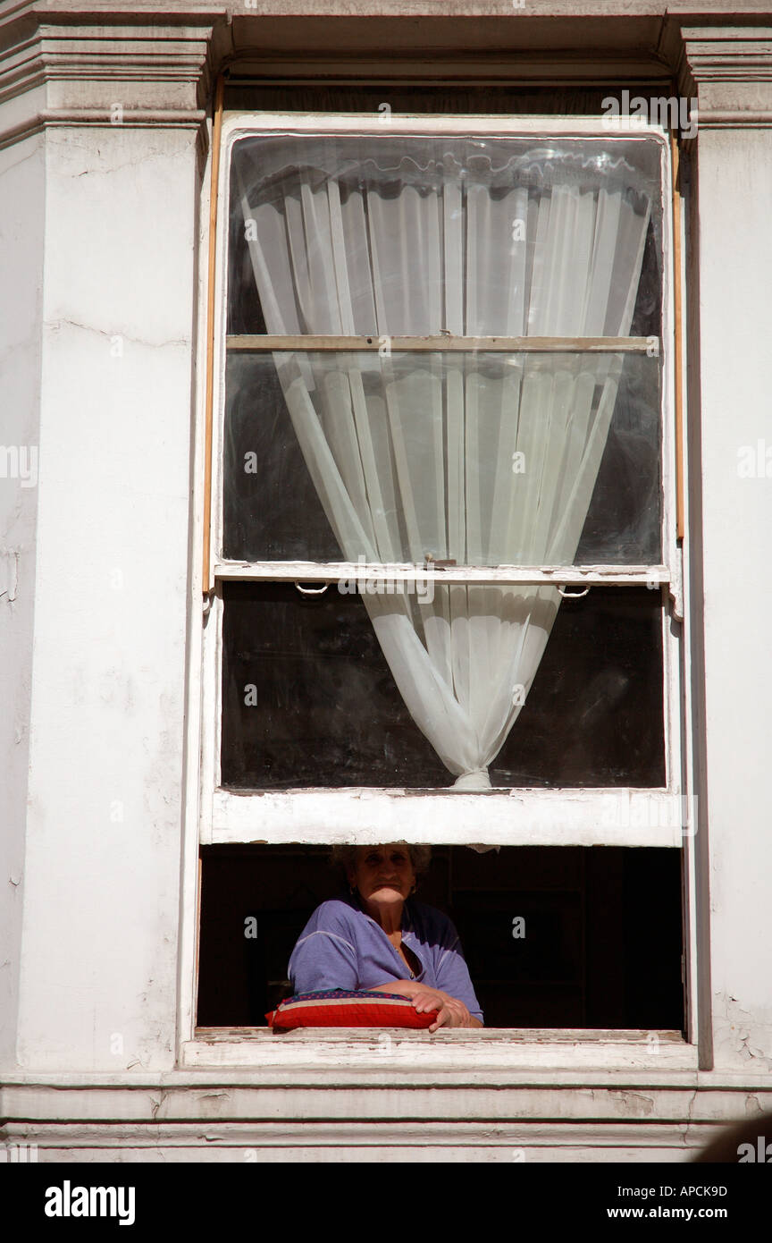 einsame Figur im Fenster beobachten das Leben draußen auf der Straße sitzen. Stockfoto