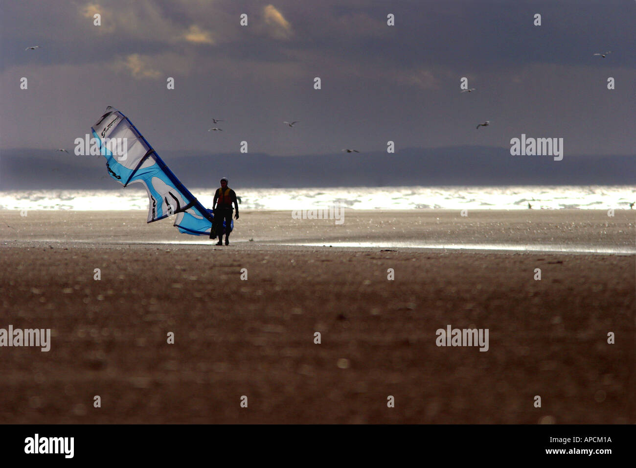 Ein Kitesurfer geht bis zum Strand an einem Nachmittag Ende des Winters, als die Sonne bricht im Westen, Ainsdale, UK. Stockfoto