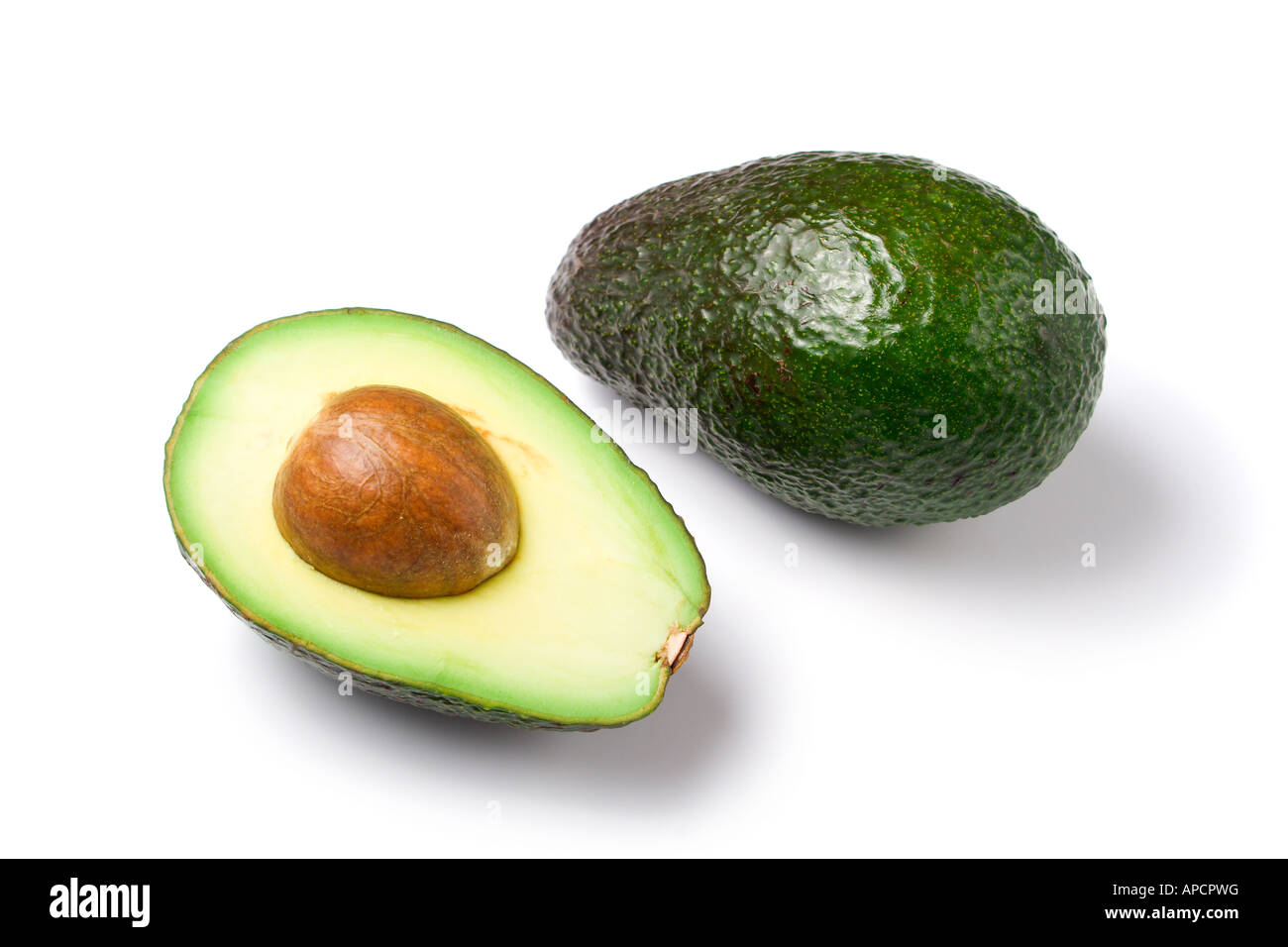 eine ganze und eine halbe Reife Avocado, mit Kern, isoliert auf weißem Hintergrund Stockfoto