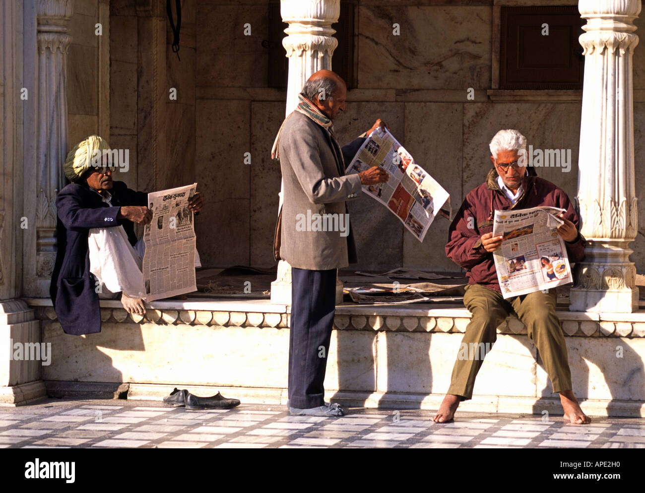 Drei Männer lesen Zeitungen im Deshnoke Tempel in der Nähe von Bikaner in Rajasthan Indien Stockfoto