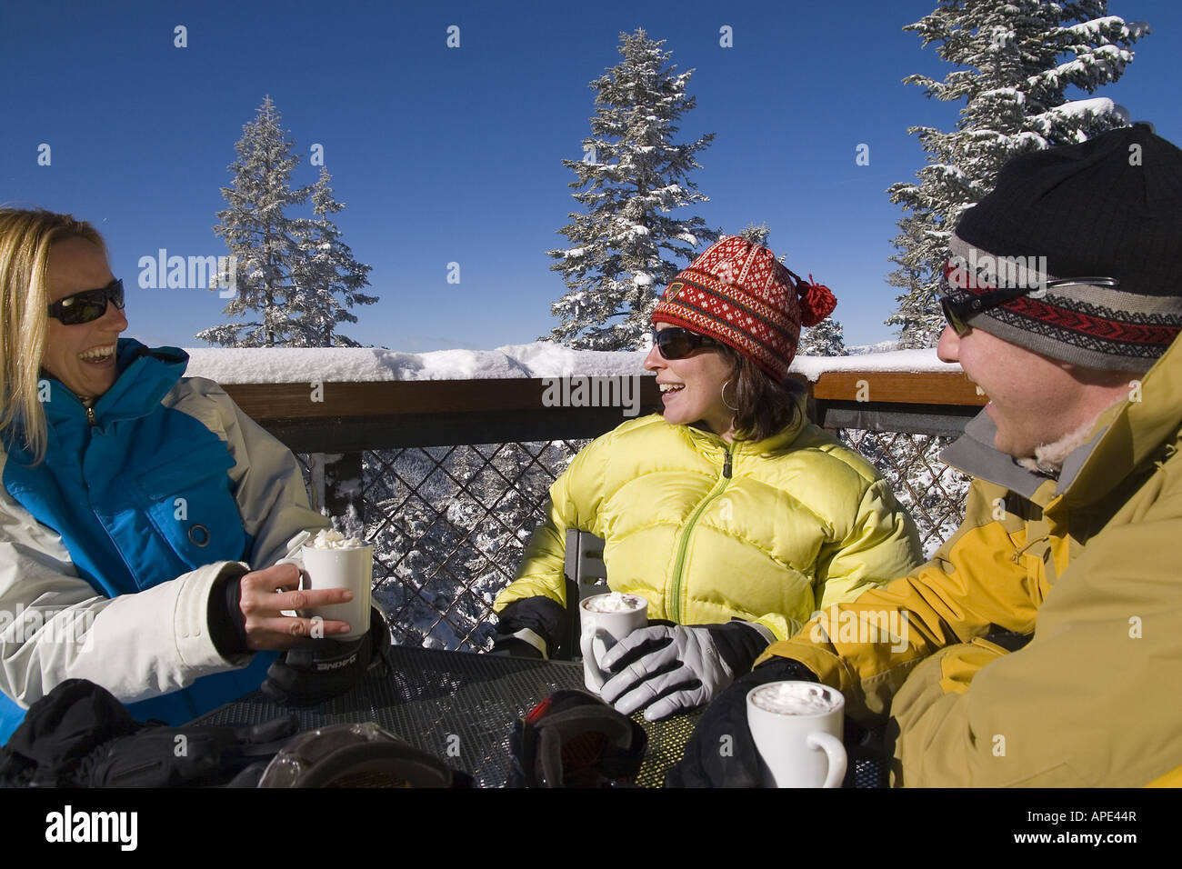 Drei Freunde genießen heißen Schokolade auf dem Deck eines Ski lodge an einem verschneiten Tag während des Gesprächs im Northstar in der Nähe von Lake Tahoe. Stockfoto