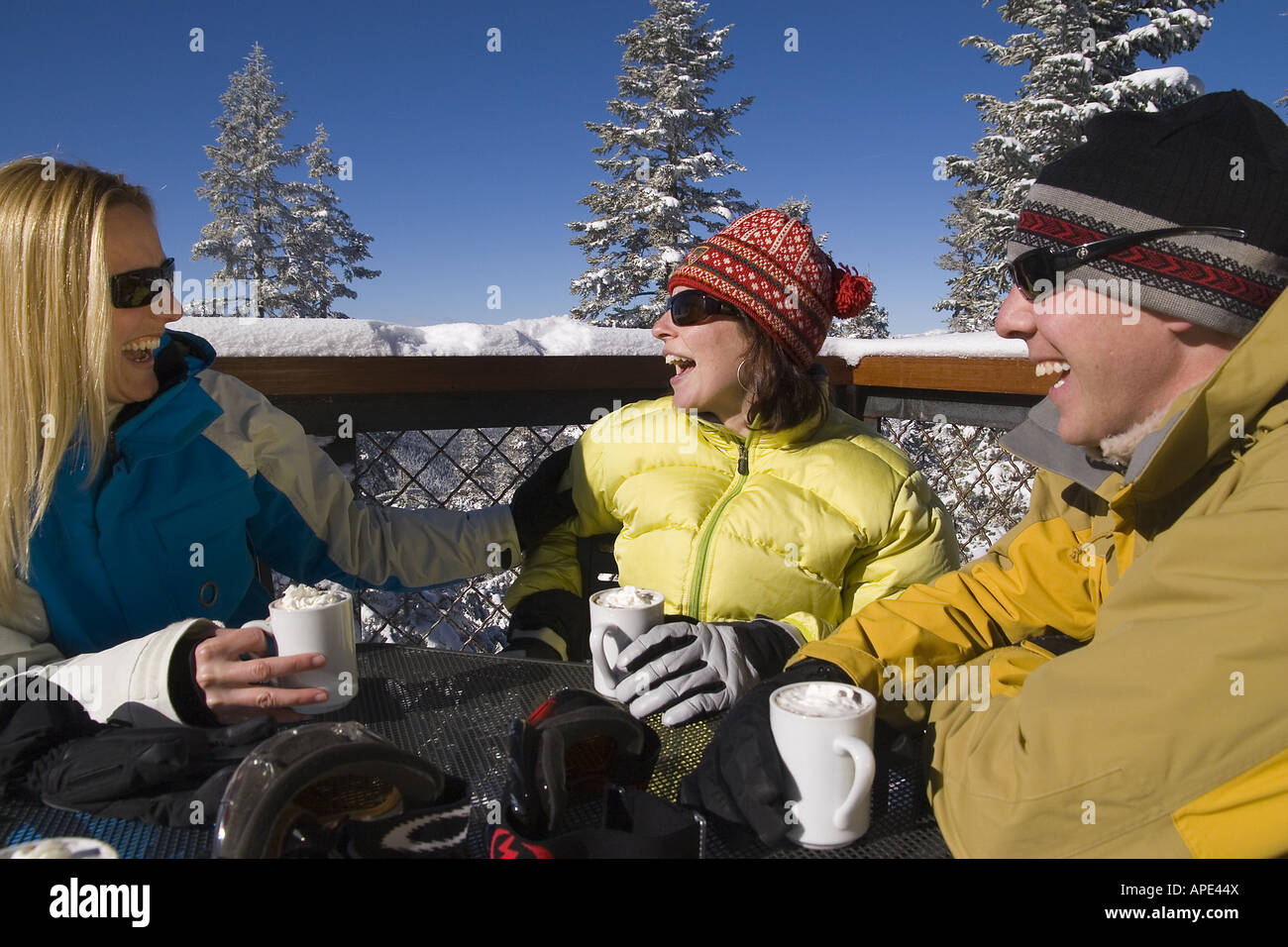Drei Freunde genießen heißen Schokolade auf dem Deck eines Ski lodge an einem verschneiten Tag während des Gesprächs im Northstar in der Nähe von Lake Tahoe. Stockfoto