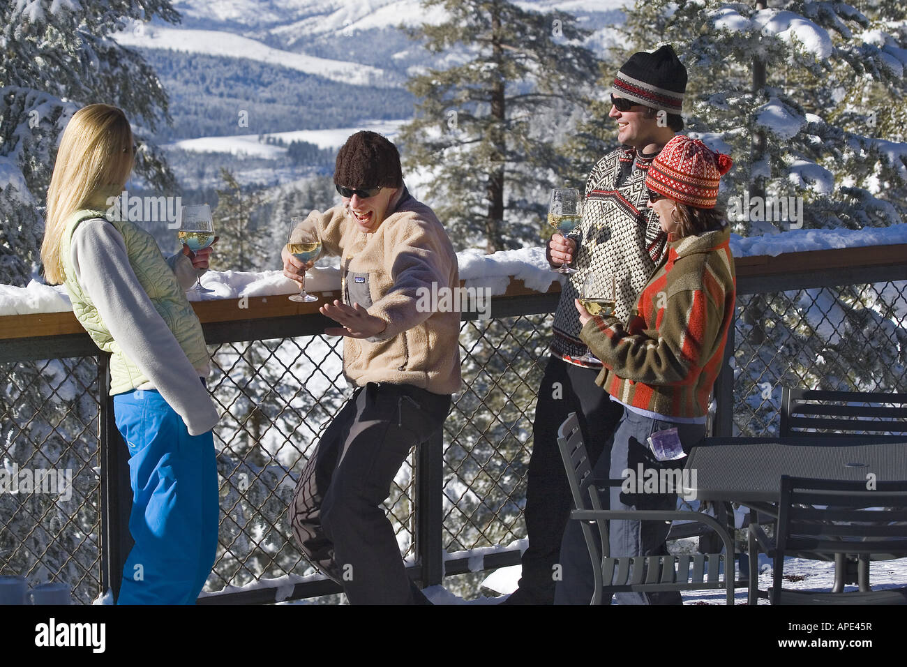 Vier Freunde genießen Weißwein auf dem Deck eines Ski lodge an einem verschneiten Tag während des Gesprächs im Northstar in der Nähe von Lake Tahoe. Stockfoto