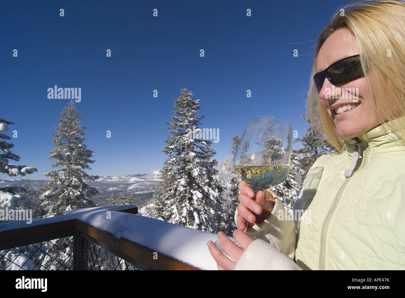 Eine Frau mit einem Glas Weißwein auf der Terrasse an eine Skihütte im Northstar Ski Resort in der Nähe von Lake Tahoe Kalifornien. Stockfoto