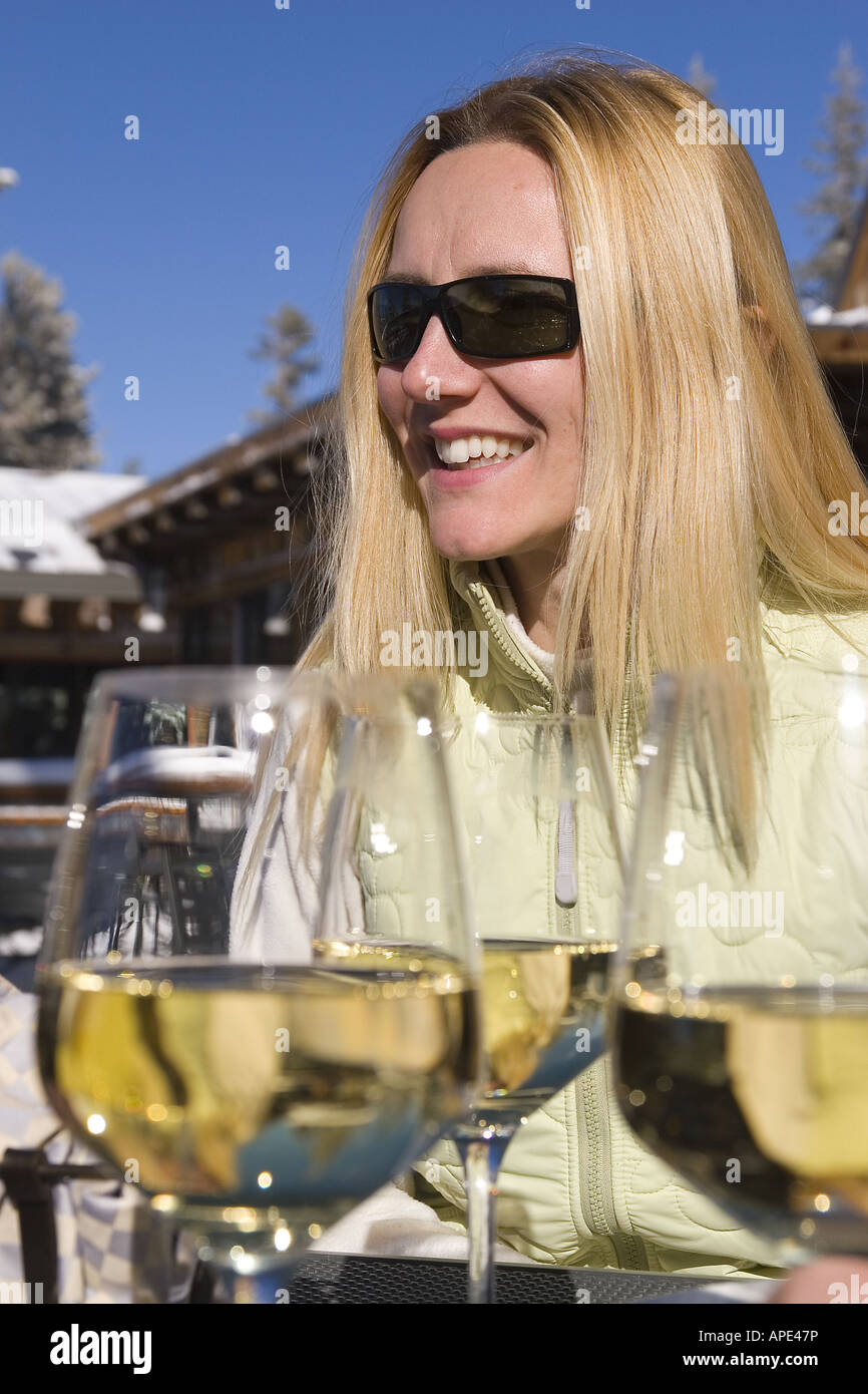 Eine Frau mit einem Glas Weißwein auf der Terrasse an eine Skihütte im Northstar Ski Resort in der Nähe von Lake Tahoe Kalifornien. Stockfoto