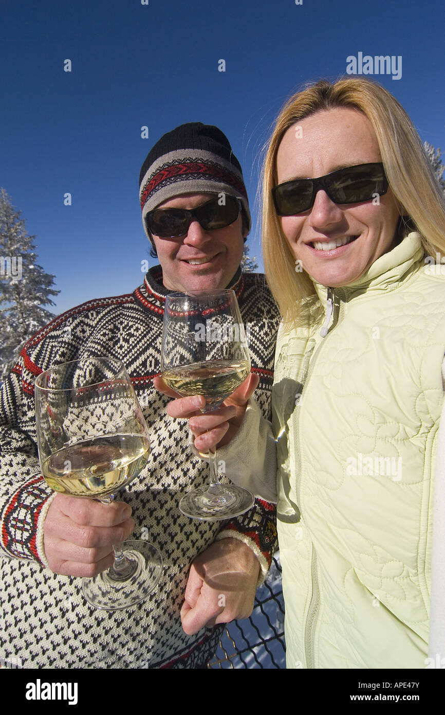 Ein paar trinken Weißwein auf dem Deck eine Ski-Hütte an einem verschneiten Tag im Northstar in der Nähe von Lake Tahoe. Stockfoto