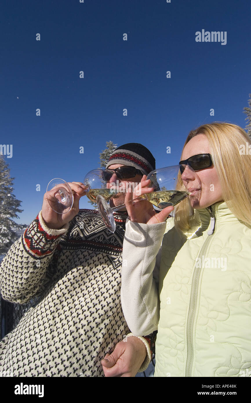 Ein paar trinken Weißwein auf dem Deck eine Ski-Hütte an einem verschneiten Tag im Northstar in der Nähe von Lake Tahoe. Stockfoto