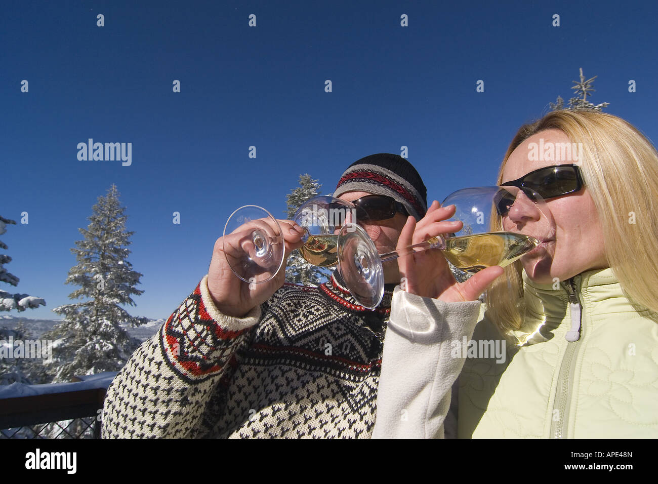 Ein paar trinken Weißwein auf dem Deck eine Ski-Hütte an einem verschneiten Tag im Northstar in der Nähe von Lake Tahoe. Stockfoto