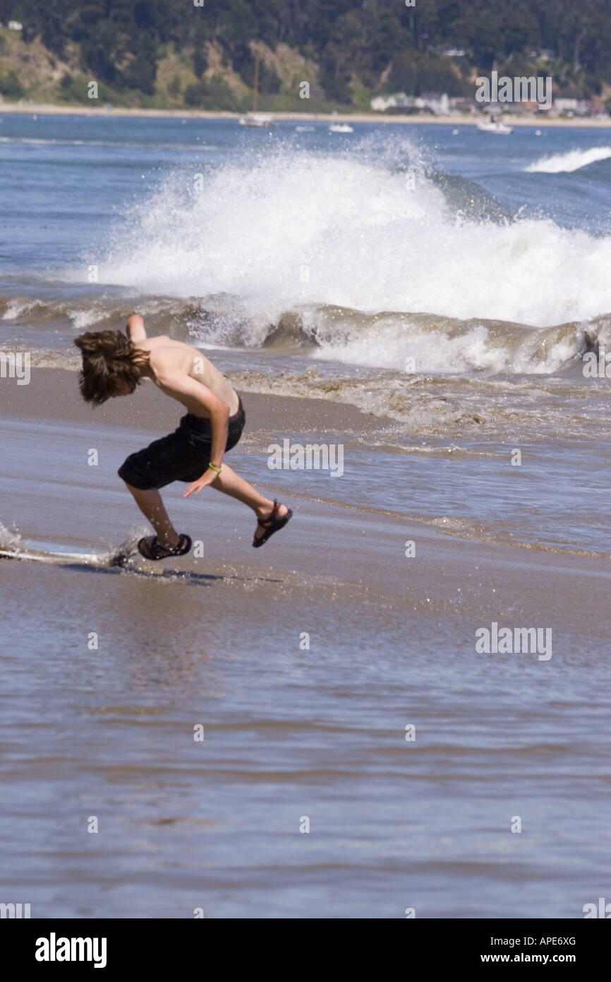 Ein kleiner Junge skim Boarding am Strand auf den Pazifischen Ozean in Santa Cruz, Kalifornien Stockfoto