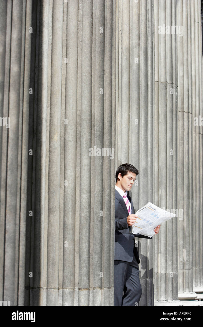 Geschäftsmann, stehen außerhalb Gebäude zwischen Säulen lesen Zeitung Stockfoto