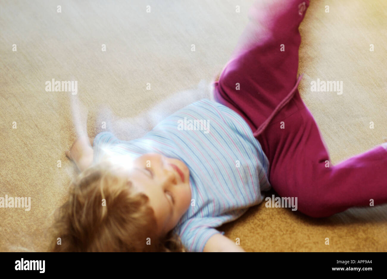 Verschwommene Aufnahme von jungen Mädchen wälzen auf Teppich Stockfoto
