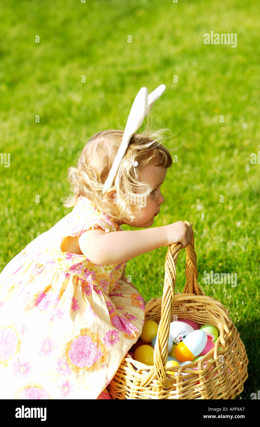 Zwei Jahre altes Mädchen hält Osterkorb tragen Hasenohren Stockfoto