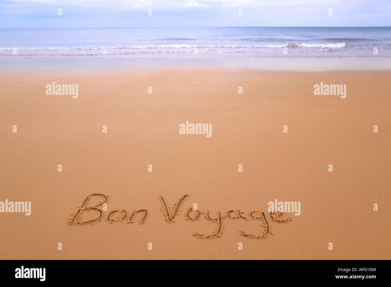 Bon Voyage geschrieben in Sand auf einem goldenen Sandstrand, Meer und Horizont in der Ferne Stockfoto
