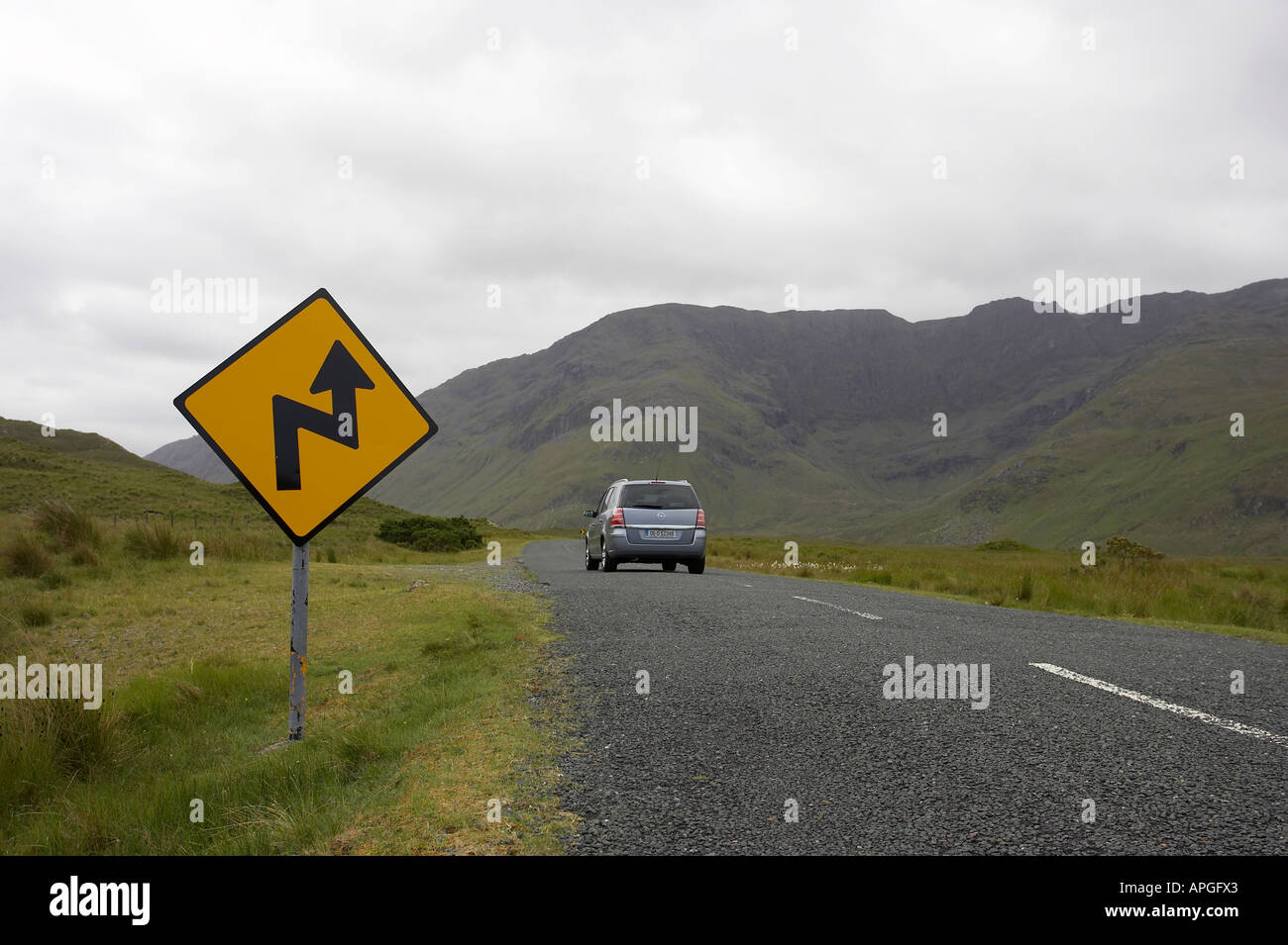 gelbe und schwarze Diamanten Warnung Reihe von gefährlichen Ecken Verkehrszeichen und Auto auf Bergstraße Connemara Stockfoto