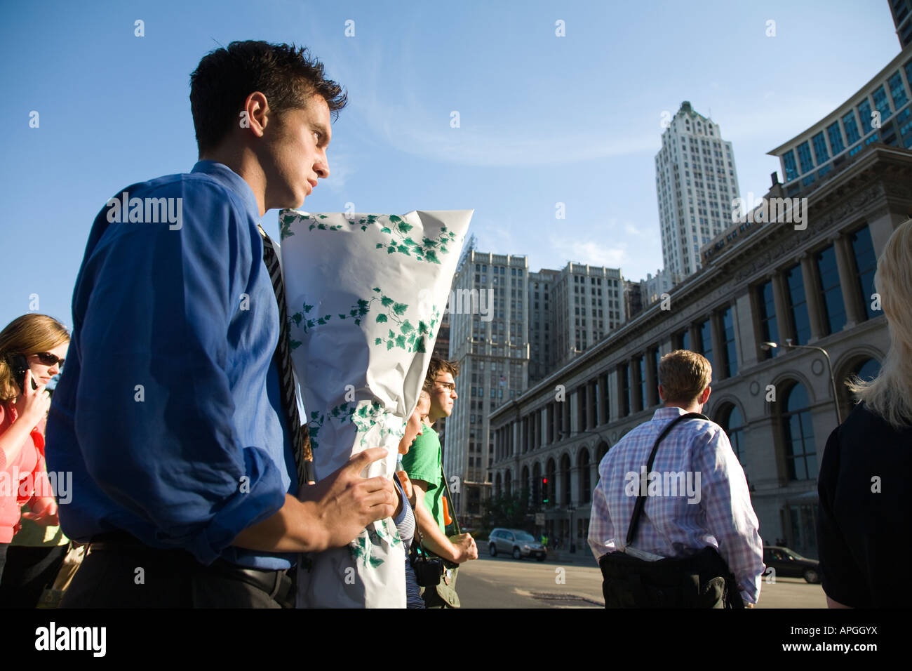 ILLINOIS-Chicago Junge Erwachsene männliche Beteiligung gewickelt Blumenstrauß warten auf Ampel Innenstadt ändern Stockfoto