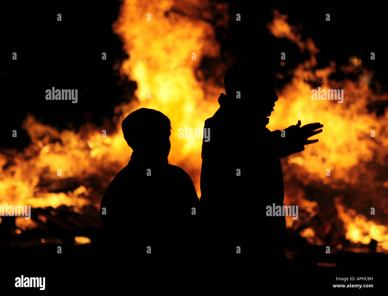 Silhouette von zwei Menschen, die gegen eines brennenden Feuers Stockfoto