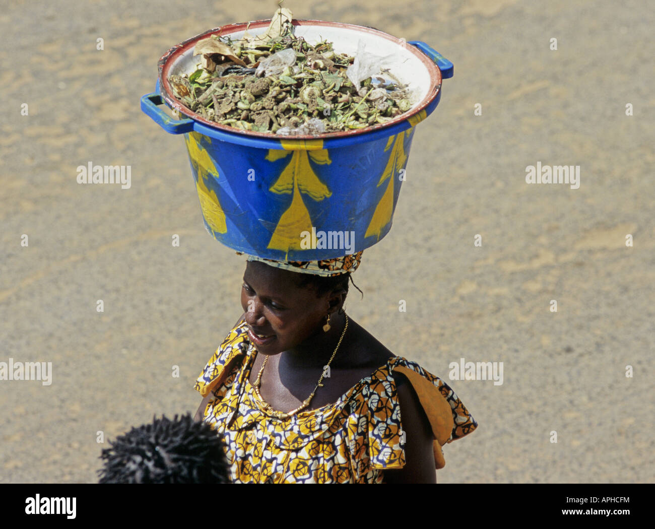 Eine Frau trägt eine Last auf dem Kopf in der Haupteinkaufsstraße in Serekunda die größte Stadt in Gambia Stockfoto