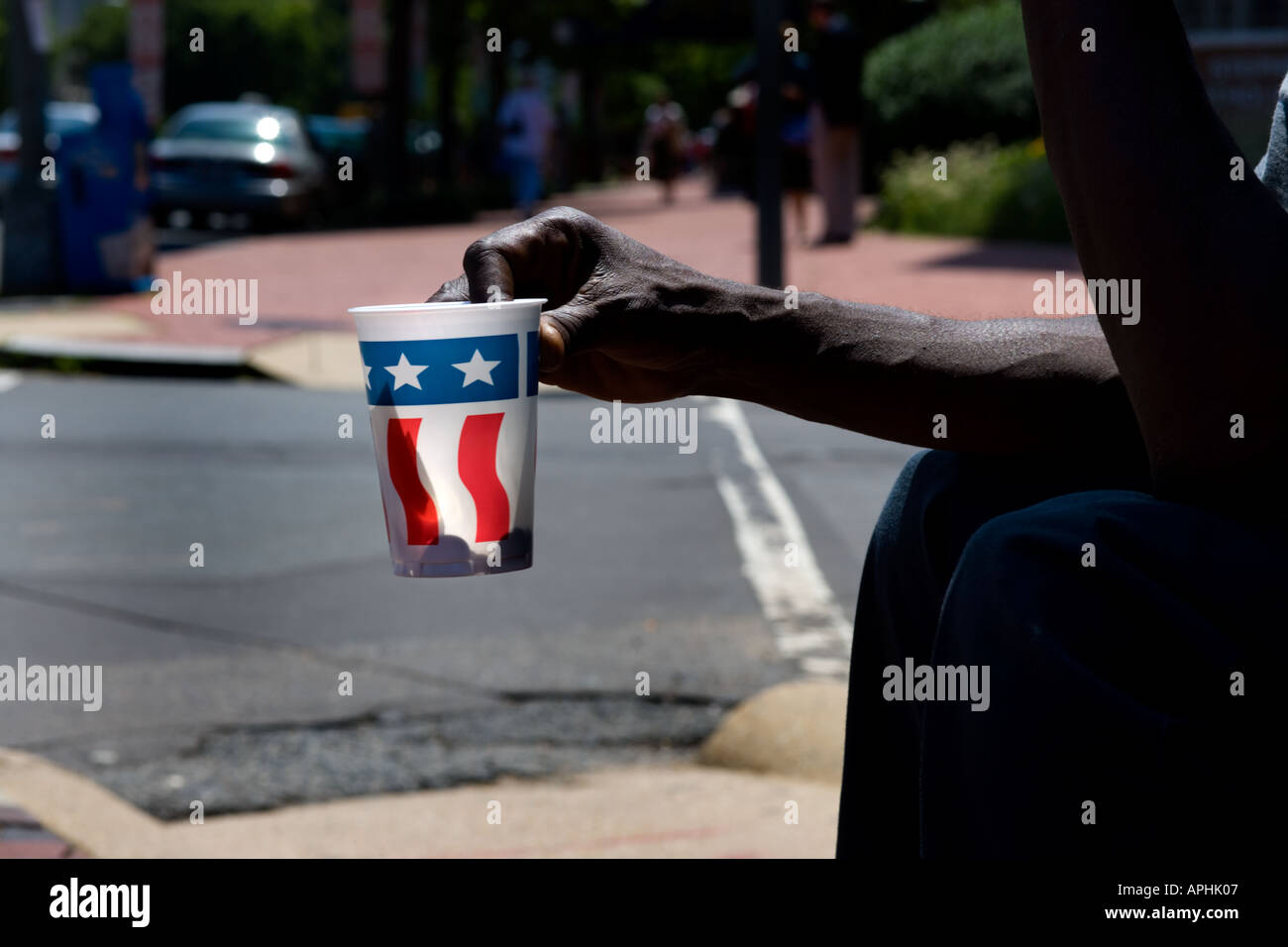 Arm des Bettlers, Bettler, Pappbecher mit uns durchhalten Flag Dekor auf Washington DC Straße. Licht mit Schatten des Geldes zurück. Stockfoto