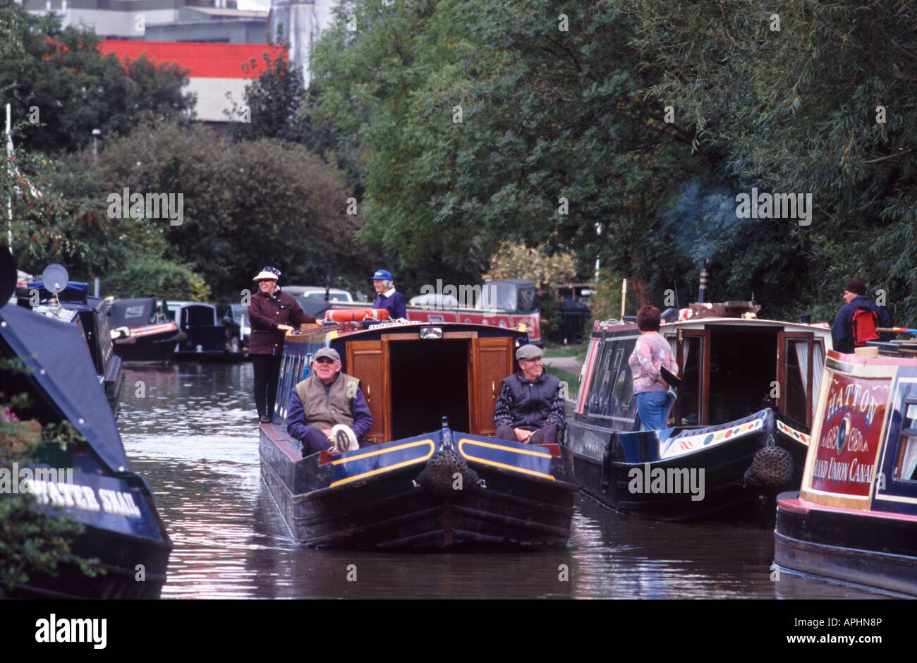 Zwei reife Männer sitzen auf dem Vordeck ein Narrowboat mit zwei lächelnde Frauen an der Spitze, Banbury, Oxfordshire, England lächelnd Stockfoto