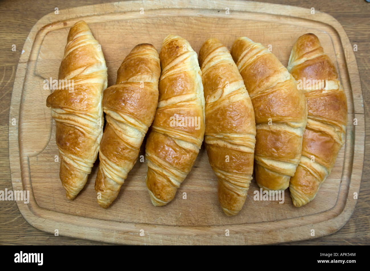 sechs frisch gebackene französische Croissants auf hölzernen Platte bereit zum Frühstück gegessen werden Stockfoto