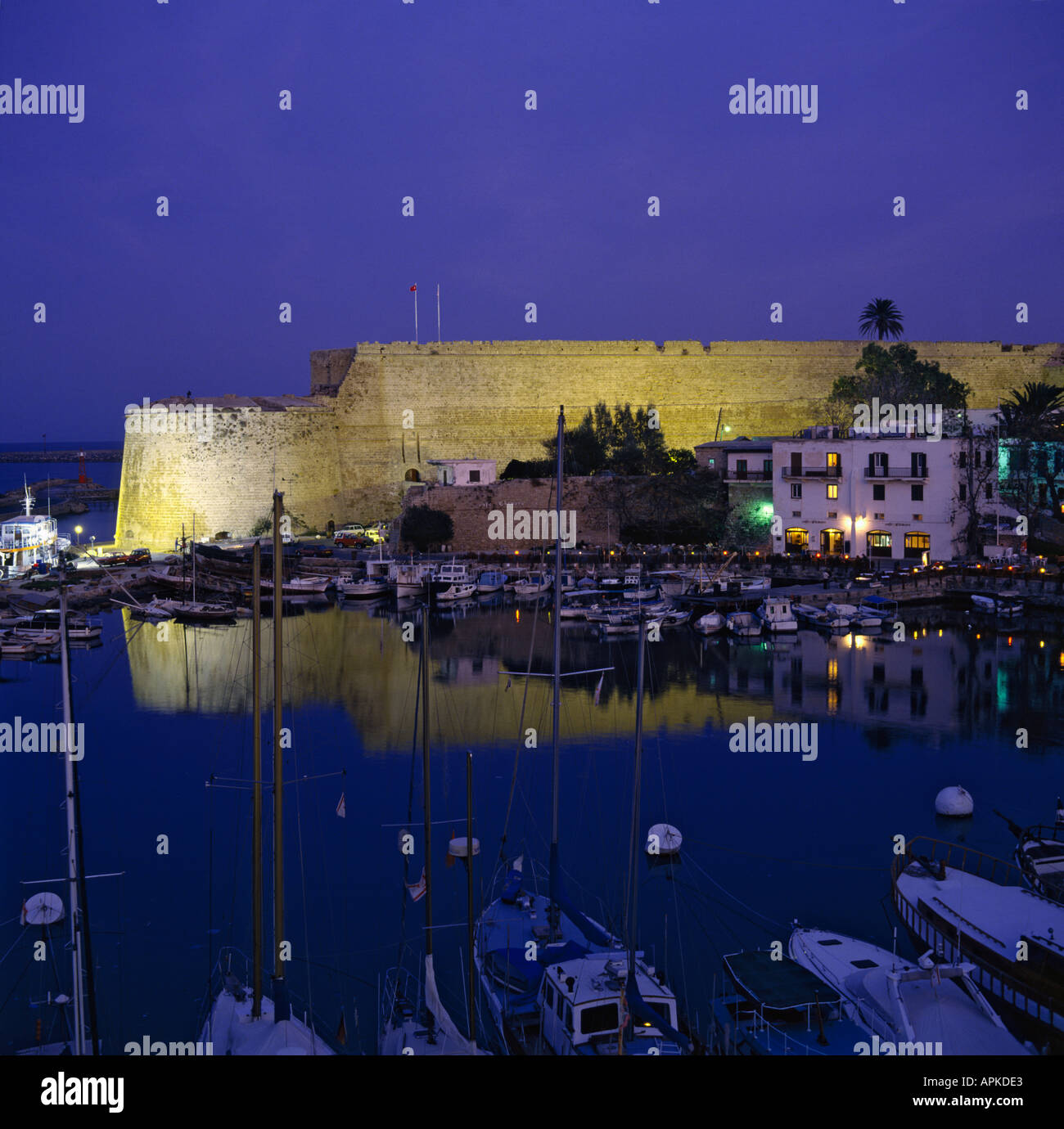 Abenddämmerung Blick auf Burgmauern durch Flutlicht beleuchtet und reflektiert im Hafen von Kyrenia Stadt türkischen Nordzypern Stockfoto