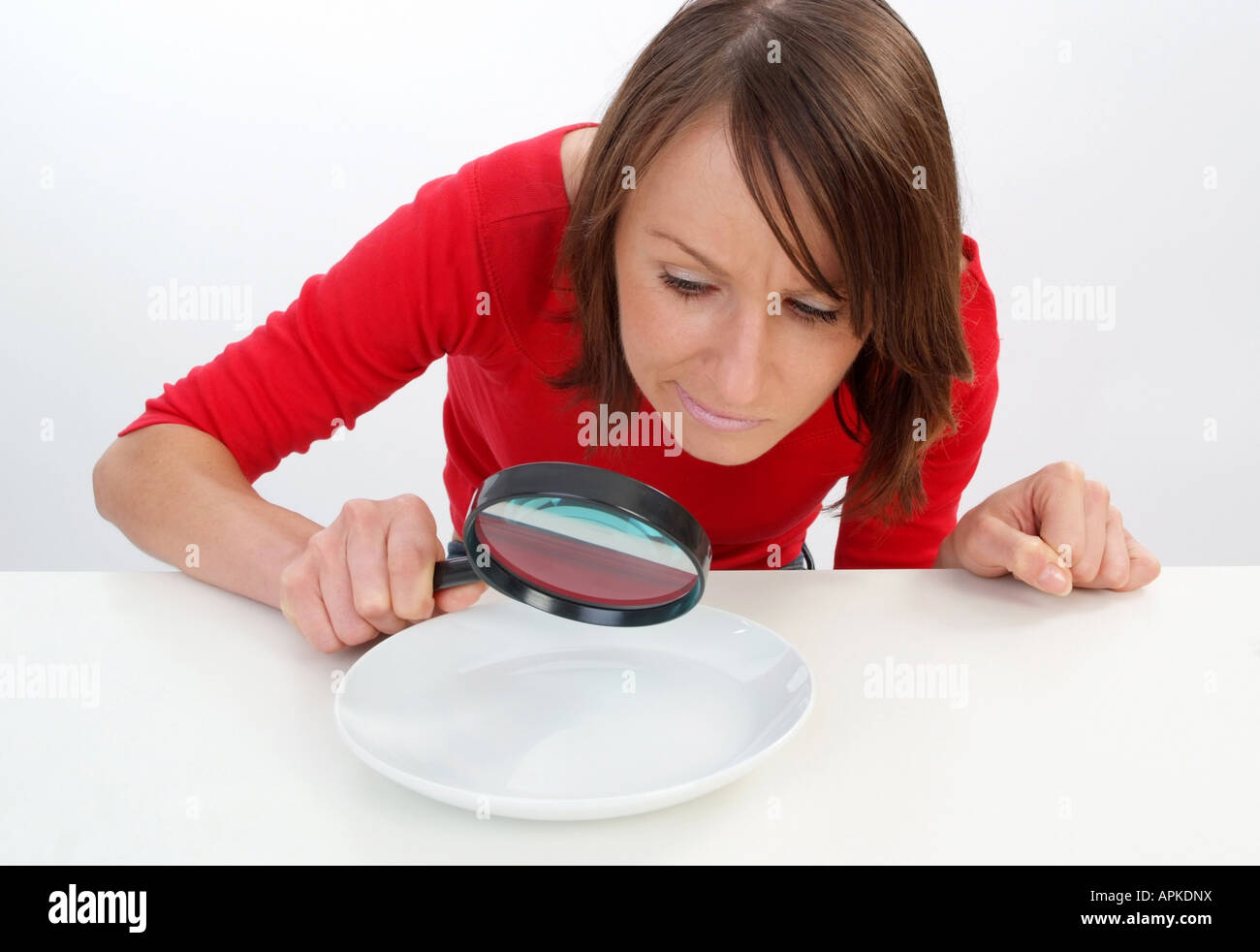 Frau auf der Suche nach etwas zu Essen bei leeren Teller Stockfoto