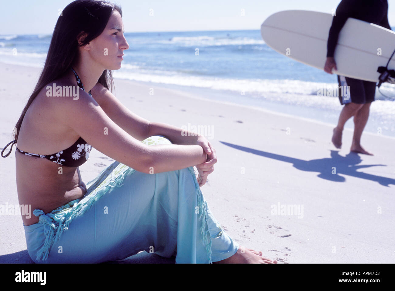 Junge Frau sitzt am Strand mit Surfer, Long Island, USA Stockfoto