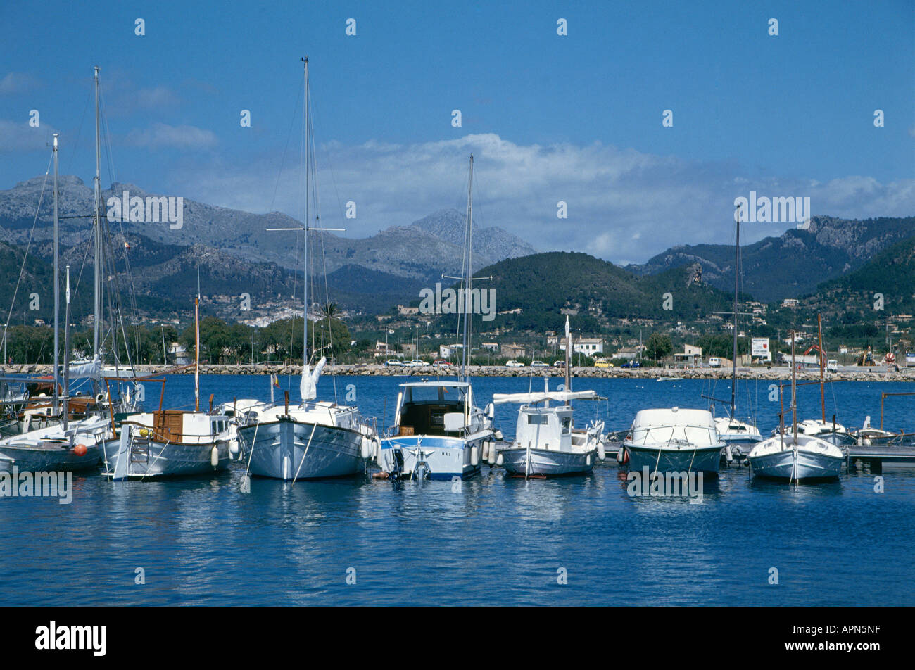 Eine Linie von Yachten und Fischerboote liegen vor Anker in der Bucht im Hafen von Port d Andratx mit Häusern am Fuße der Berge im Hintergrund Stockfoto