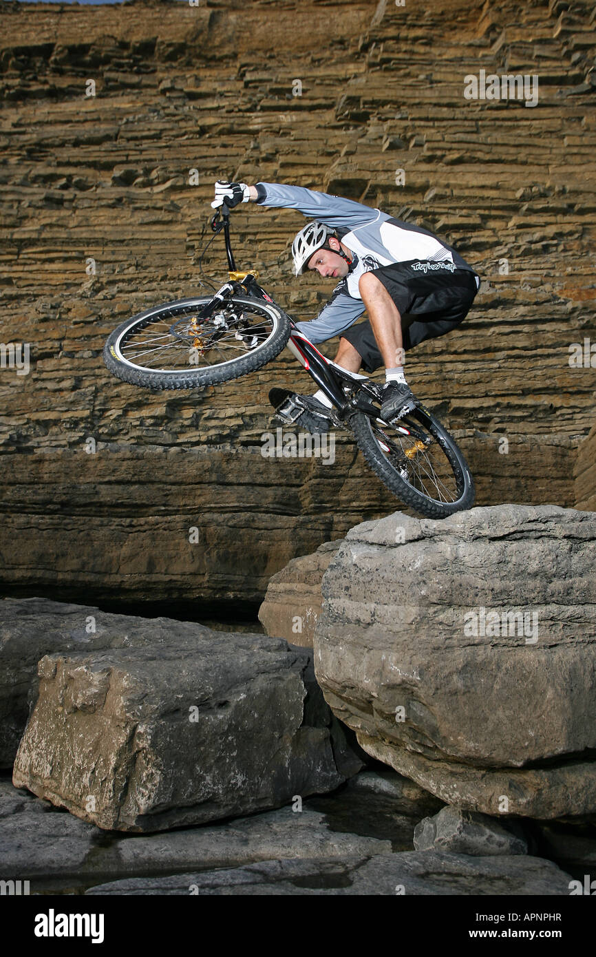 Ein Mountainbiker funktioniert ein Stunt auf einem Felsen. Stockfoto