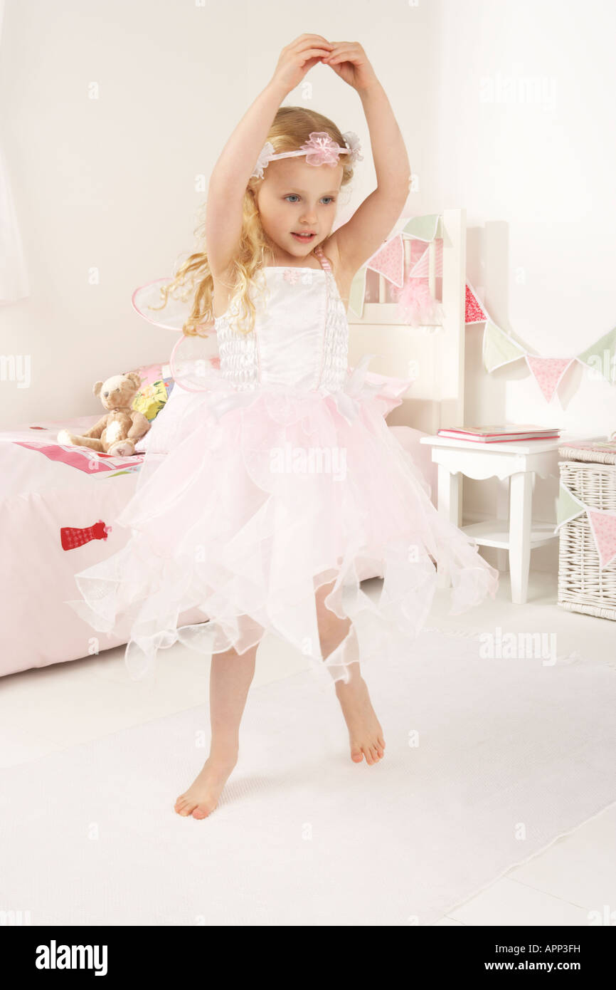 ein Mädchen spielt, putzt sich in ihrem Schlafzimmer und ist als eine weiße Fee verkleidet, wie sie in dem Raum tanzt Stockfoto
