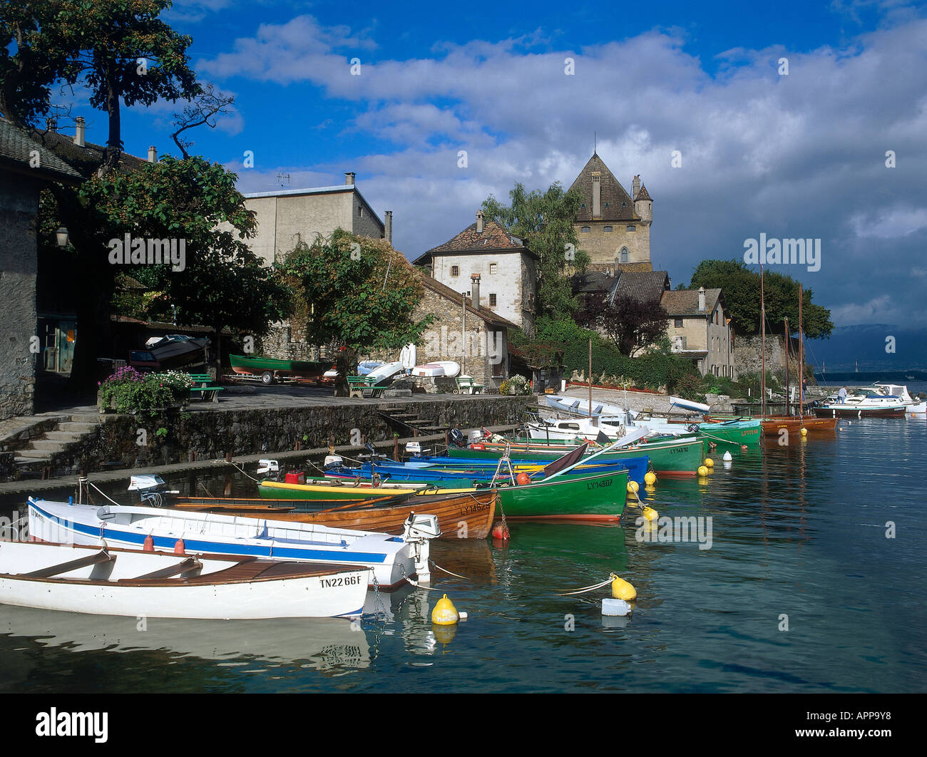 Kleine Boote an den Ufern des ummauerten Fischerei Hafen von Yvoire am französischen Ufer des Lac Leman droht im Hintergrund Schloss aus dem 14. Jahrhundert gefesselt Stockfoto