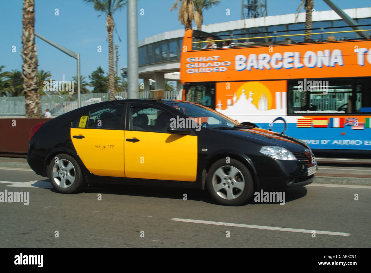 Seitenansicht des ikonischen gelben und schwarzen spanischen Taxi & Fahrer vorbei an einem offenen Barcelona Sightseeing Tour Bus in der Straßenszene Katalonien Spanien EU Stockfoto