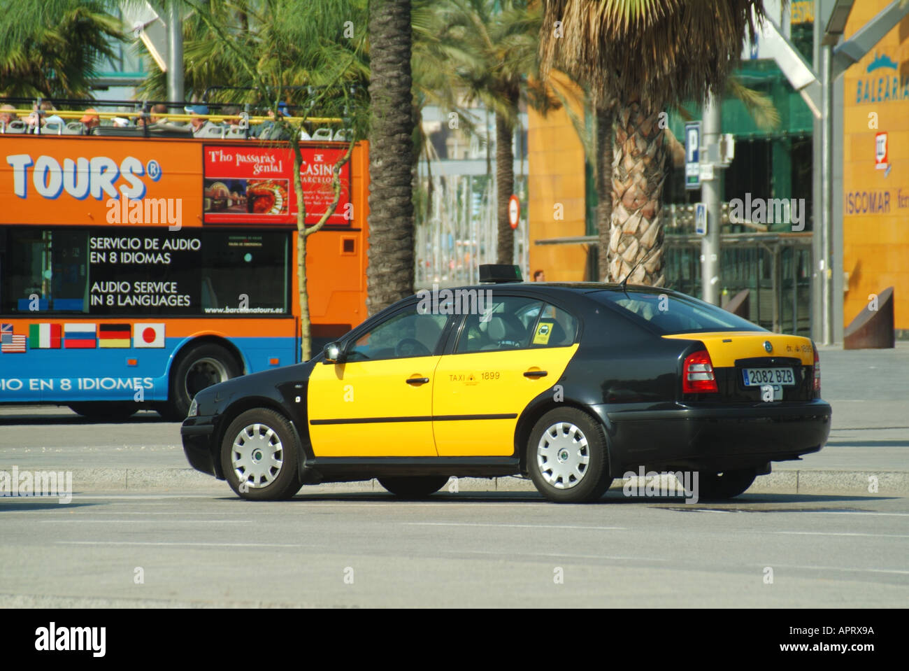 Seitenansicht des ikonischen gelben und schwarzen spanischen Taxi & Fahrer vorbei an einem offenen Barcelona Sightseeing Tour Bus in der Straßenszene Katalonien Spanien EU Stockfoto