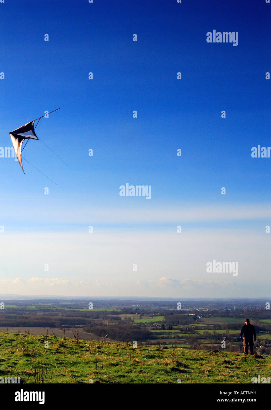 Ein Mann fliegt einen Drachen auf dem Gipfel eines Hügels in Kent, UK. Stockfoto