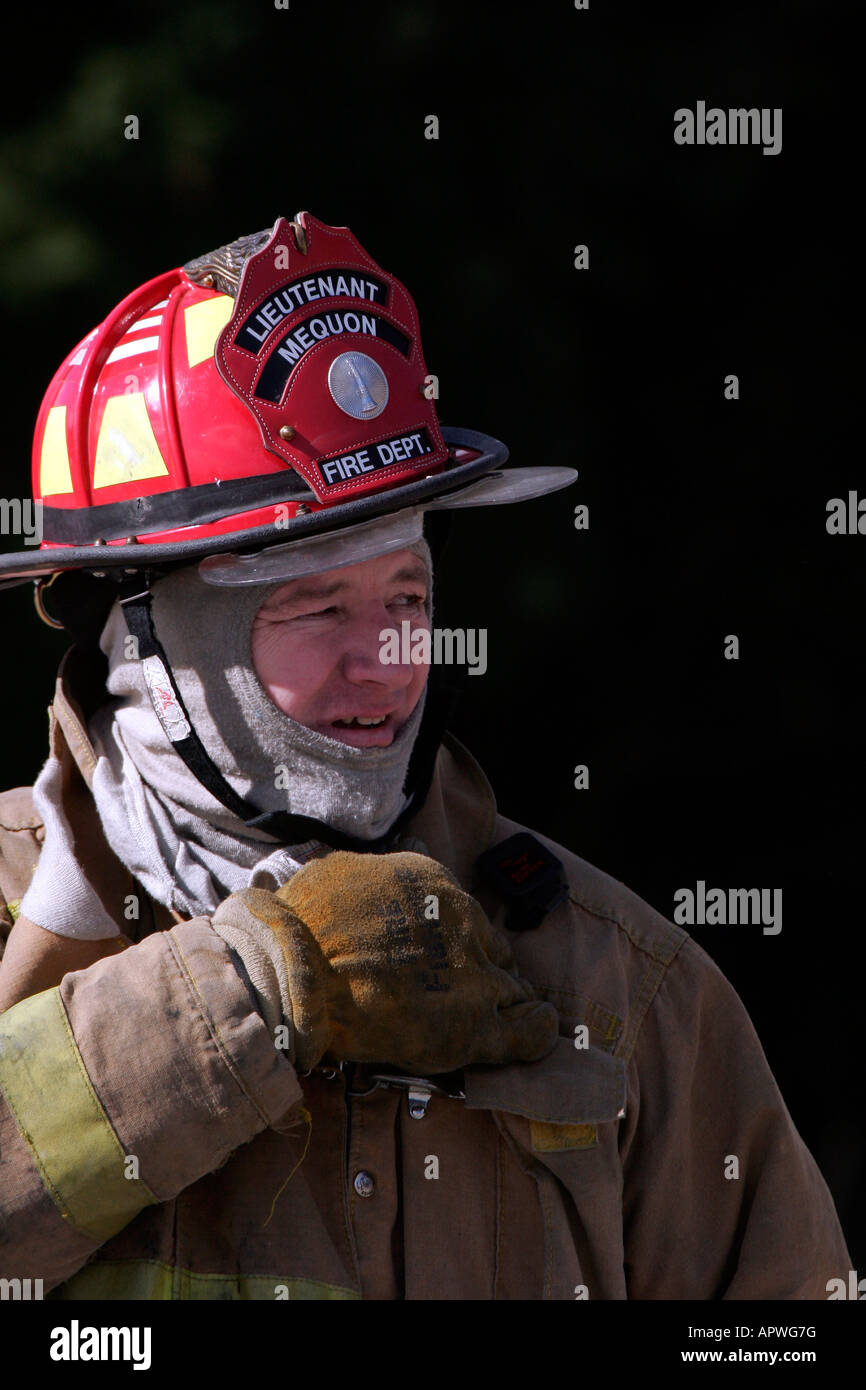 Ein amerikanischer Leutnant Feuerwehrmann für die Stadt von Mequon Wisconsin mit roten Helm greifen das Funkgerät Stockfoto