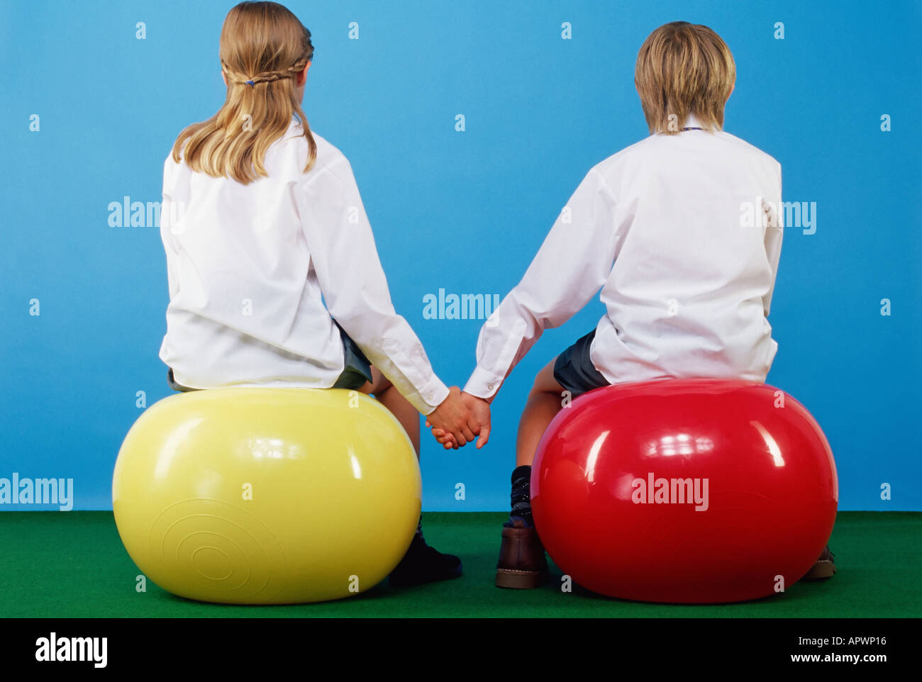 Mädchen und jungen sitzen auf Gymnastikbälle, Hand in Hand Stockfotografie Alamy