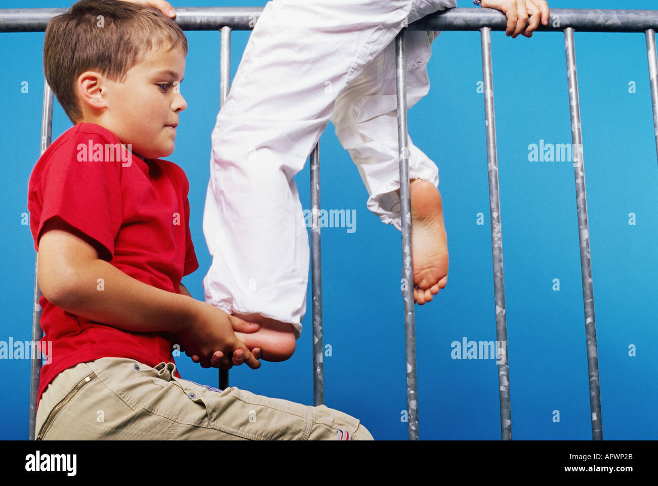 Junge hilft Freund auf ein Geländer Stockfoto