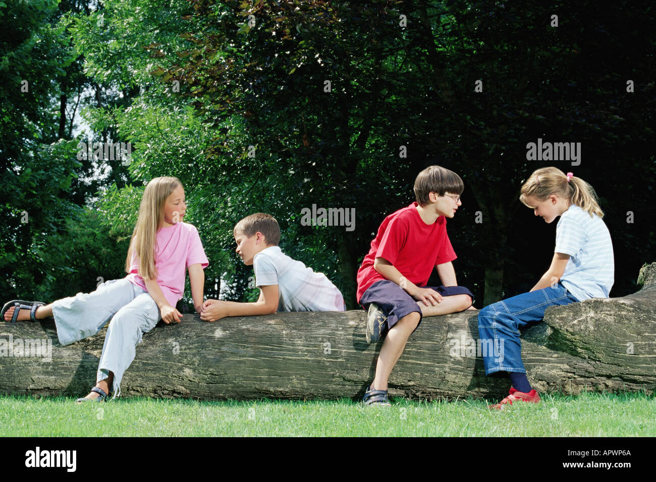 Jungen und Mädchen sitzen auf einem Baumstamm Stockfoto