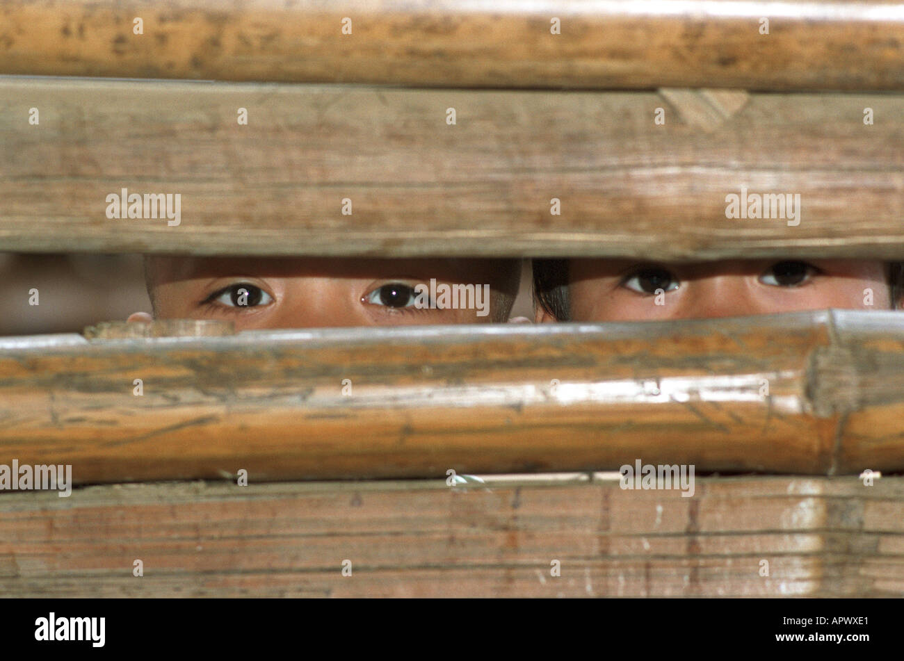 Zwei junge Karen-Flüchtlinge durch eine Bambus-Wand im Mae La Camp an der thailändischen burmesischen Grenze suchen Stockfoto