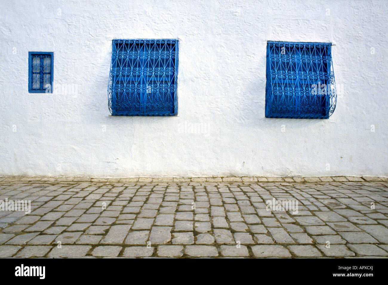 Bürgersteig in Sidi Bou Said zeigt Stein Pflasterung und drei blauen Fenstern Stockfoto